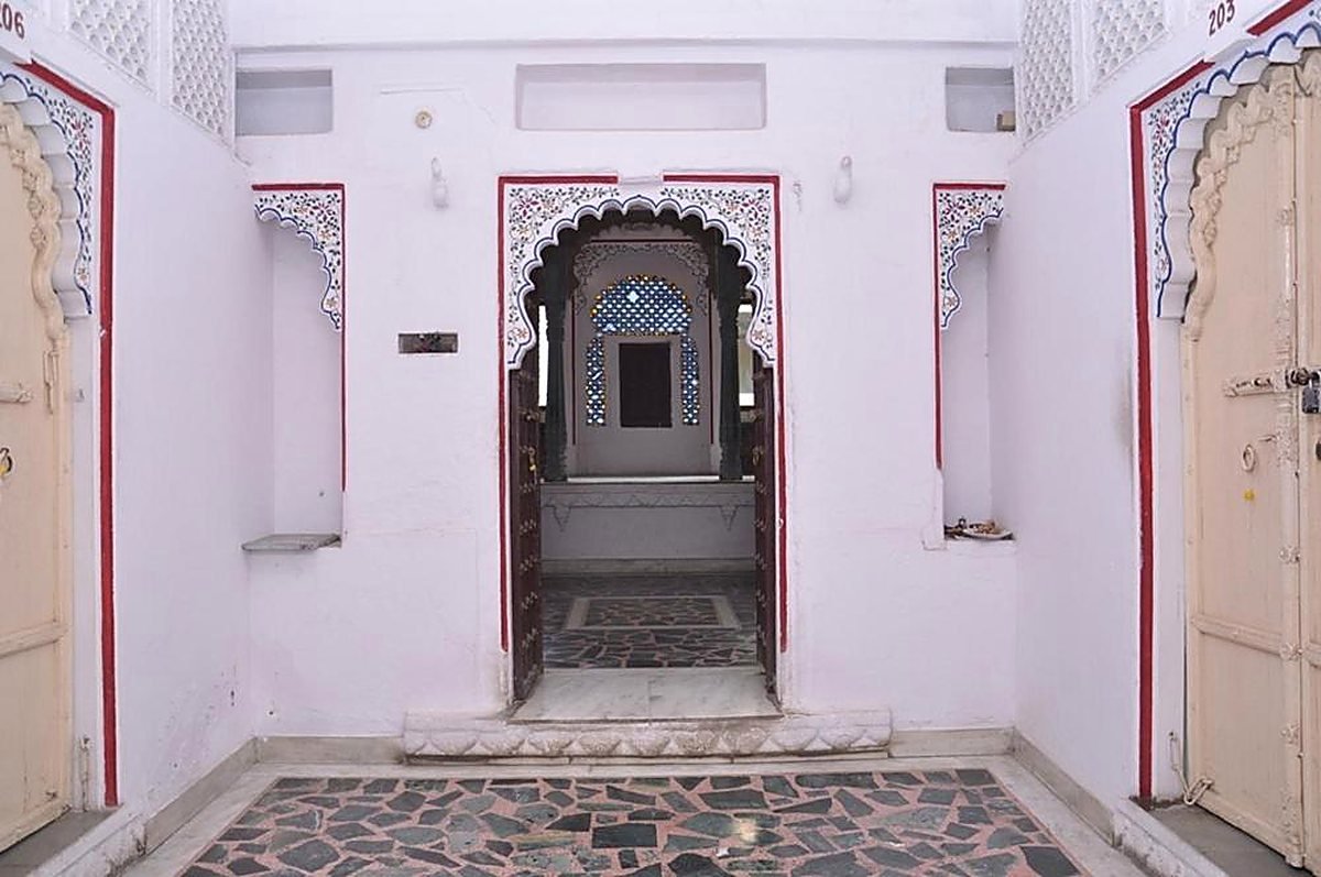 A cusped arch doorway with a painted red border opening onto an inner passage of the haveli