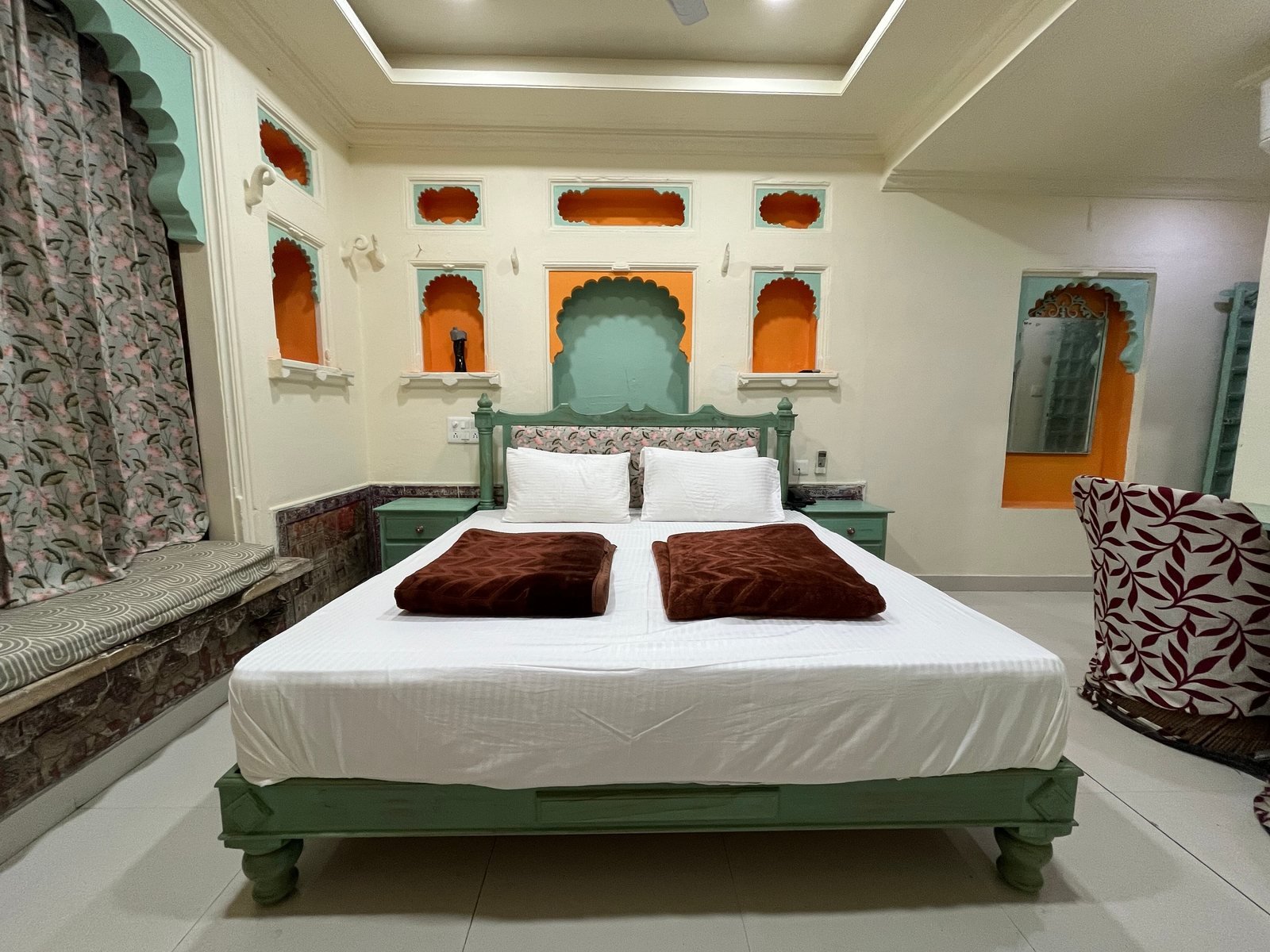 A heritage room with carved wall niches, a cusped arch above the bed and a panelled ceiling