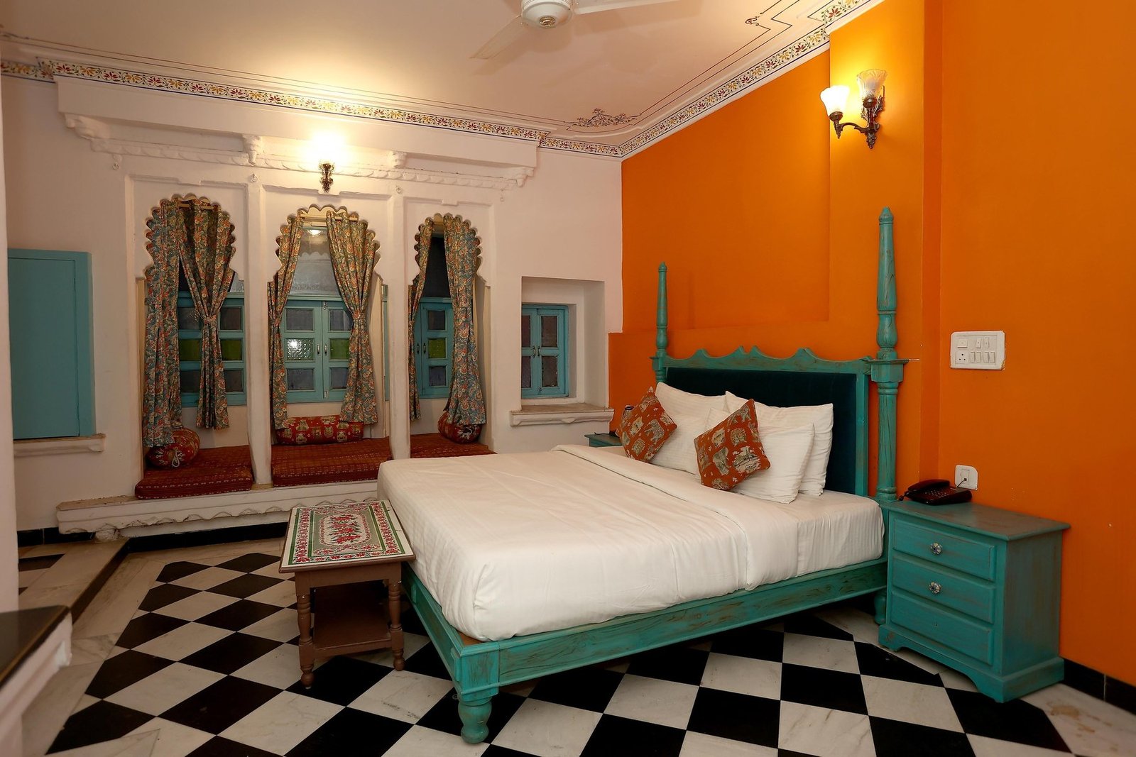 A Super Heritage Room with a turquoise four-poster bed, mirrored arched windows and a checkered stone floor