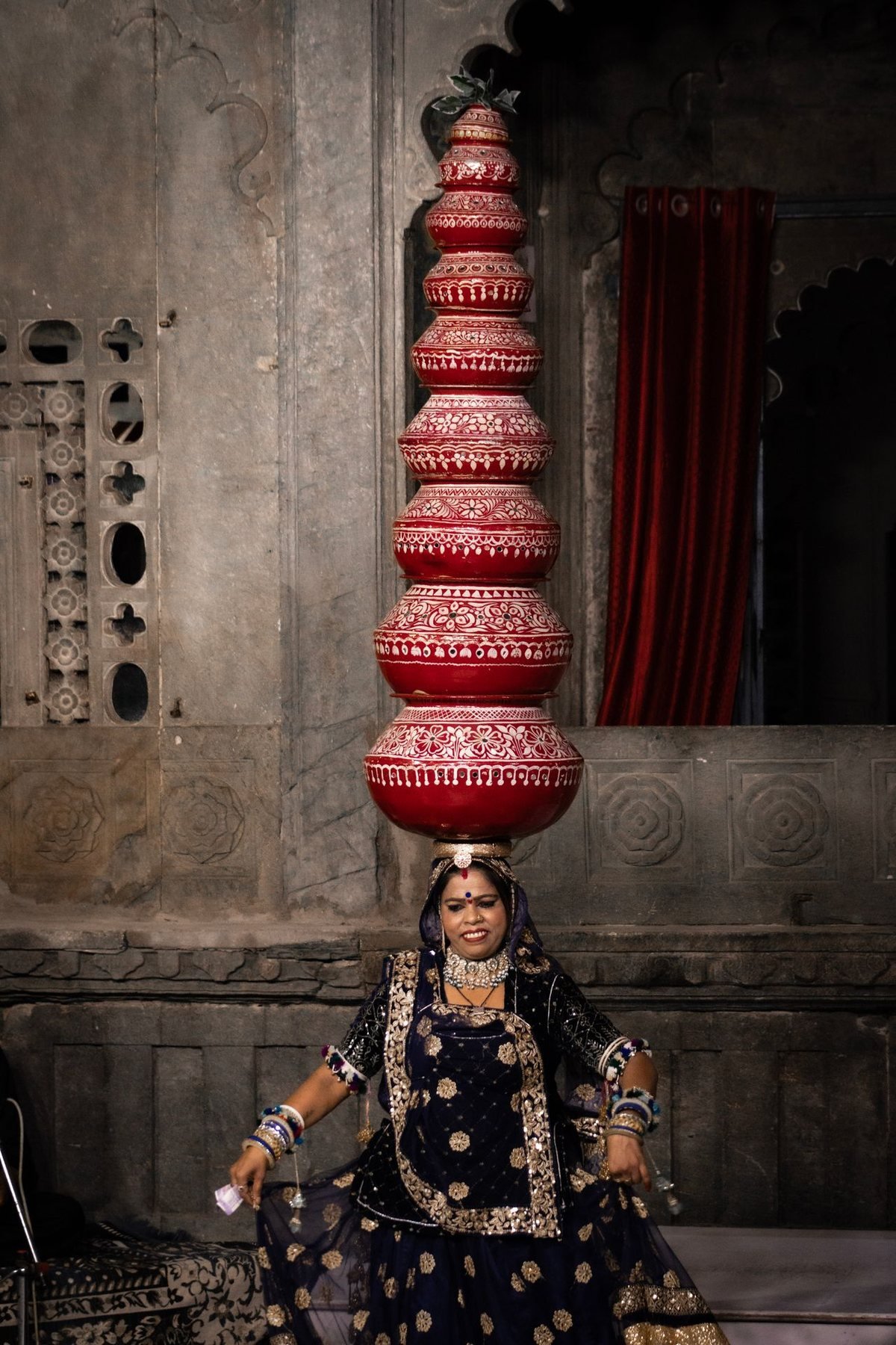 A Rajasthani folk dancer balancing a tower of painted pots during an evening performance